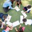 Top view of a group of students and their teacher lying on the grass and learning outdoors
