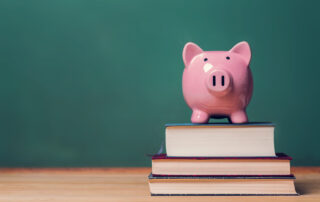 Pink Piggy bank on top of books with chalkboard in the background.