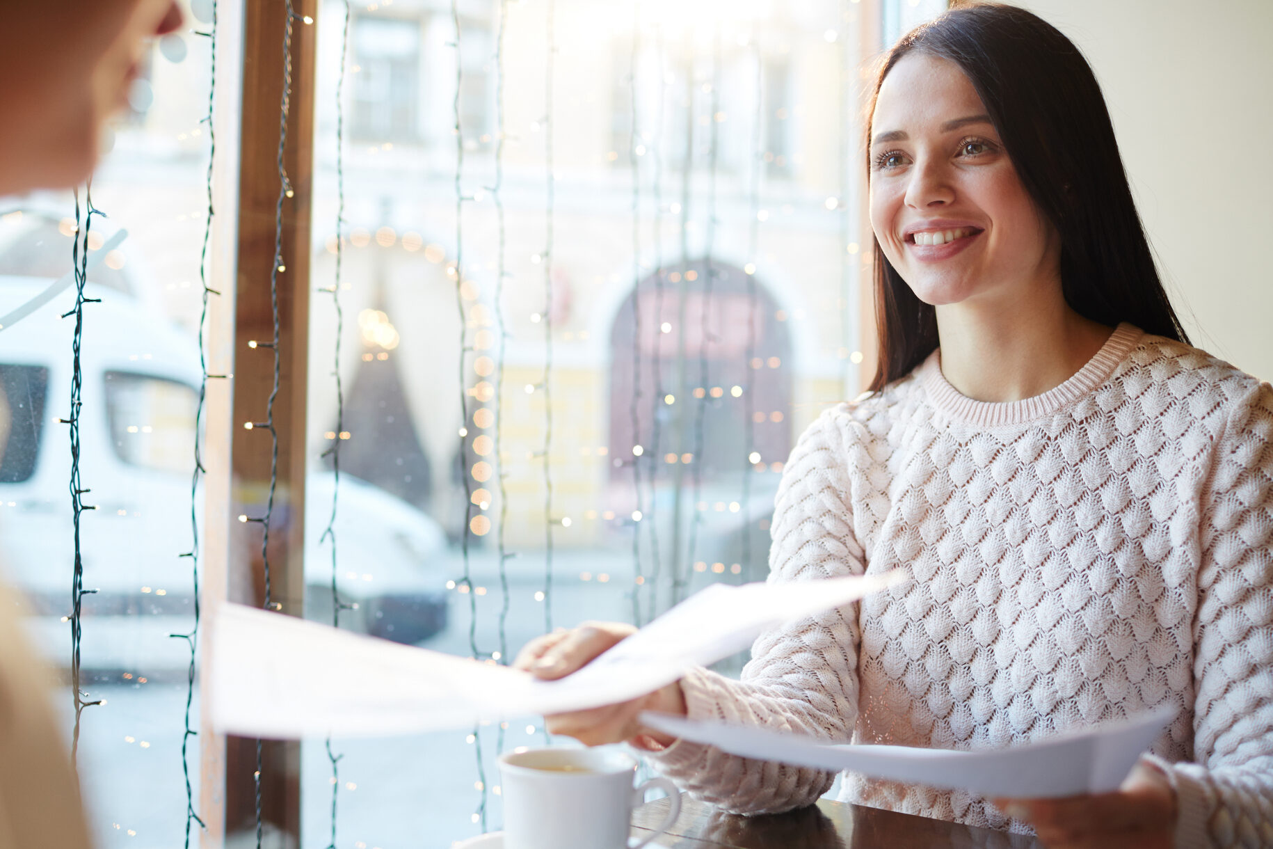 Picture of a teen handing her resume to her interviewer in a cafe for a college admissions interview