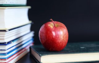 A stack of back to school books and an apple