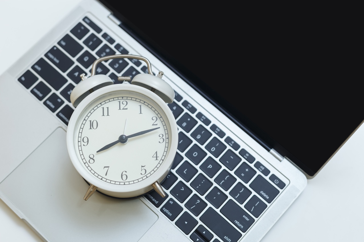 Alarm clock on computer laptop on table, demonstrating last minute sat studying.