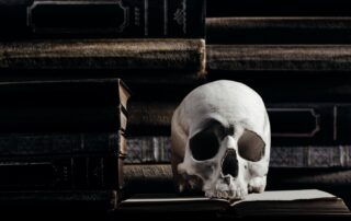 Spooky books to read for halloween, skull sitting on stacks of halloween books