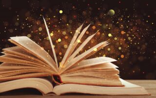 Setting reading goals in the new year—open book with glitter floating in the air.