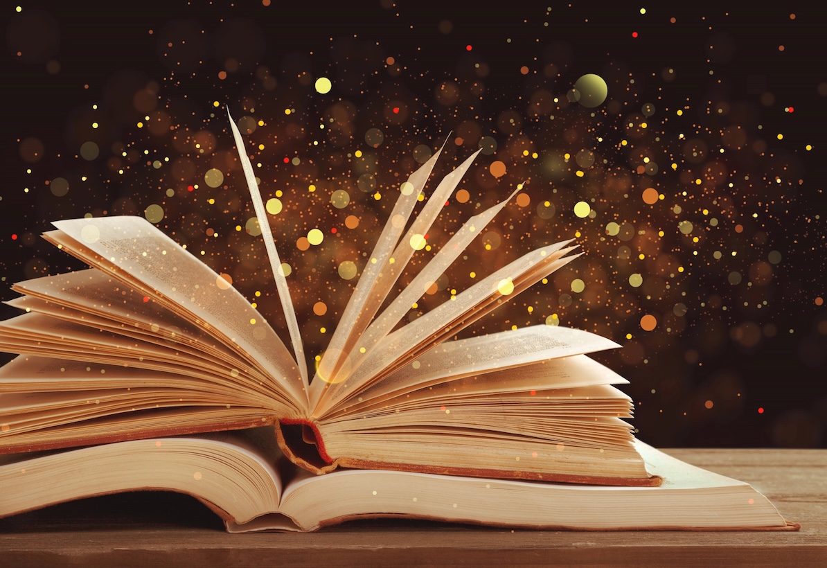 Setting reading goals in the new year—open book with glitter floating in the air.