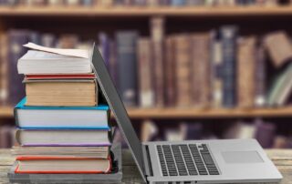 laptop leaning against stack of books in a library for reading and history learning