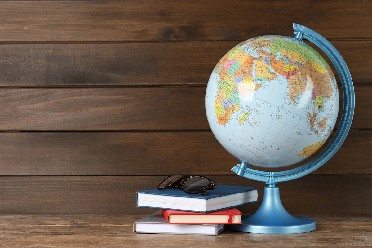 Globe, books and eyeglasses on wooden table. Books about travel.