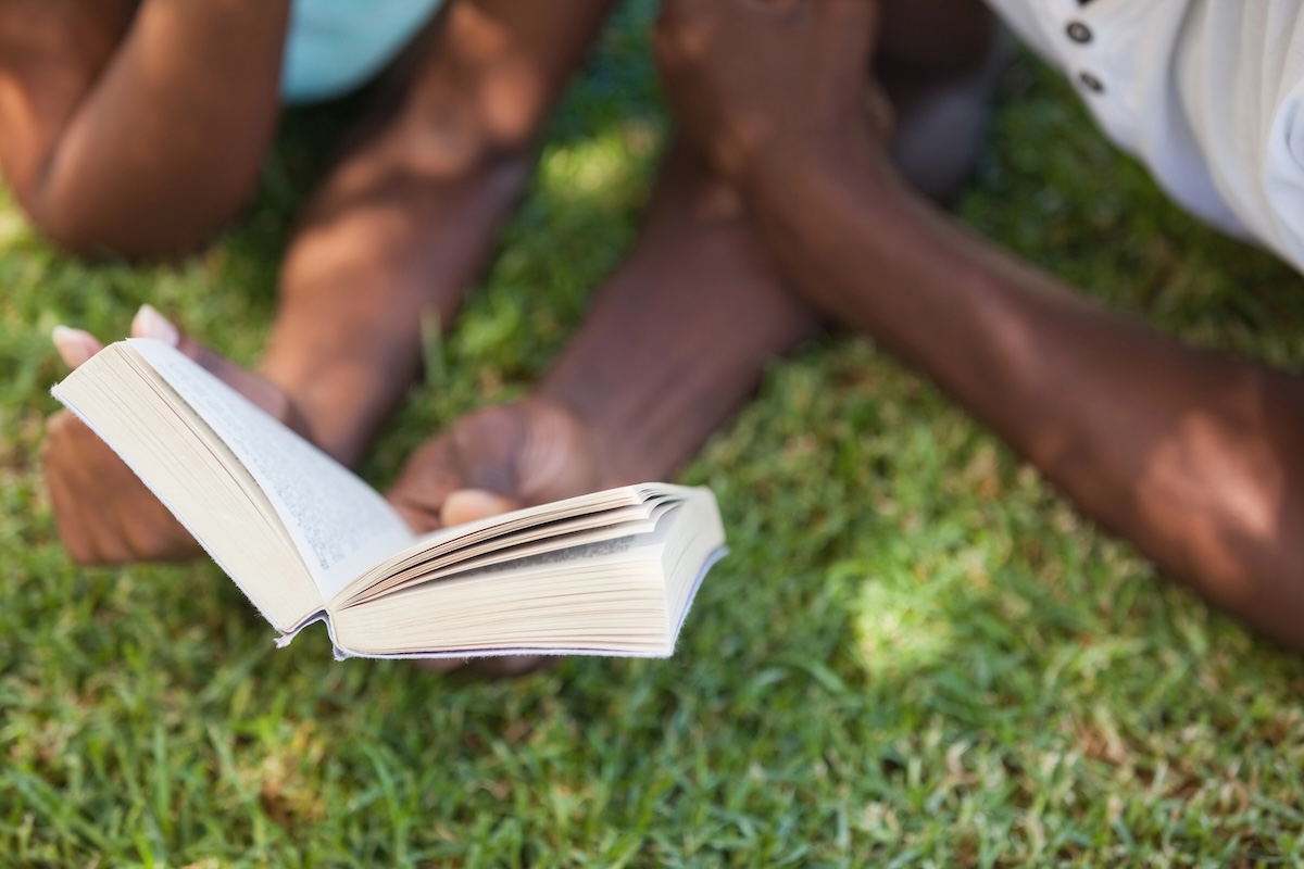 Two Black readers in the grass on a sunny June day. Books to read for Juneteenth cover image.